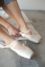 stock-photo-19632293-woman-putting-on-ballet-pointe-shoes
